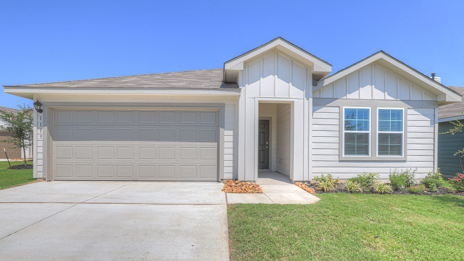 Single-story farmhouse exteriors with 2 car garage door and windows.