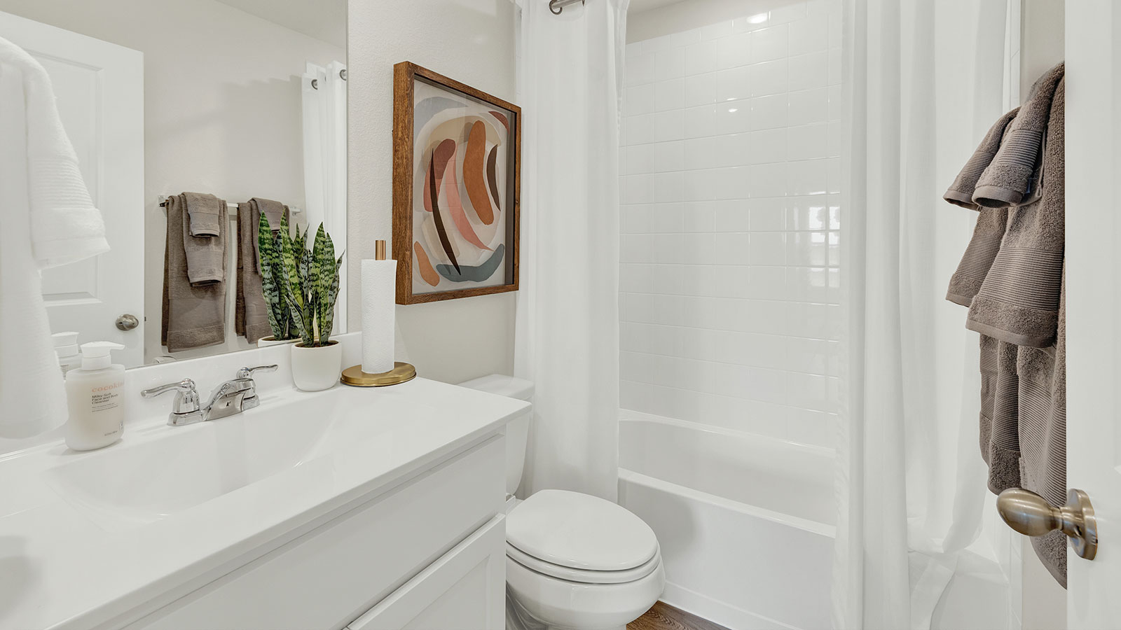Hall bathroom with vanity, toilet, and tub with tile surround.