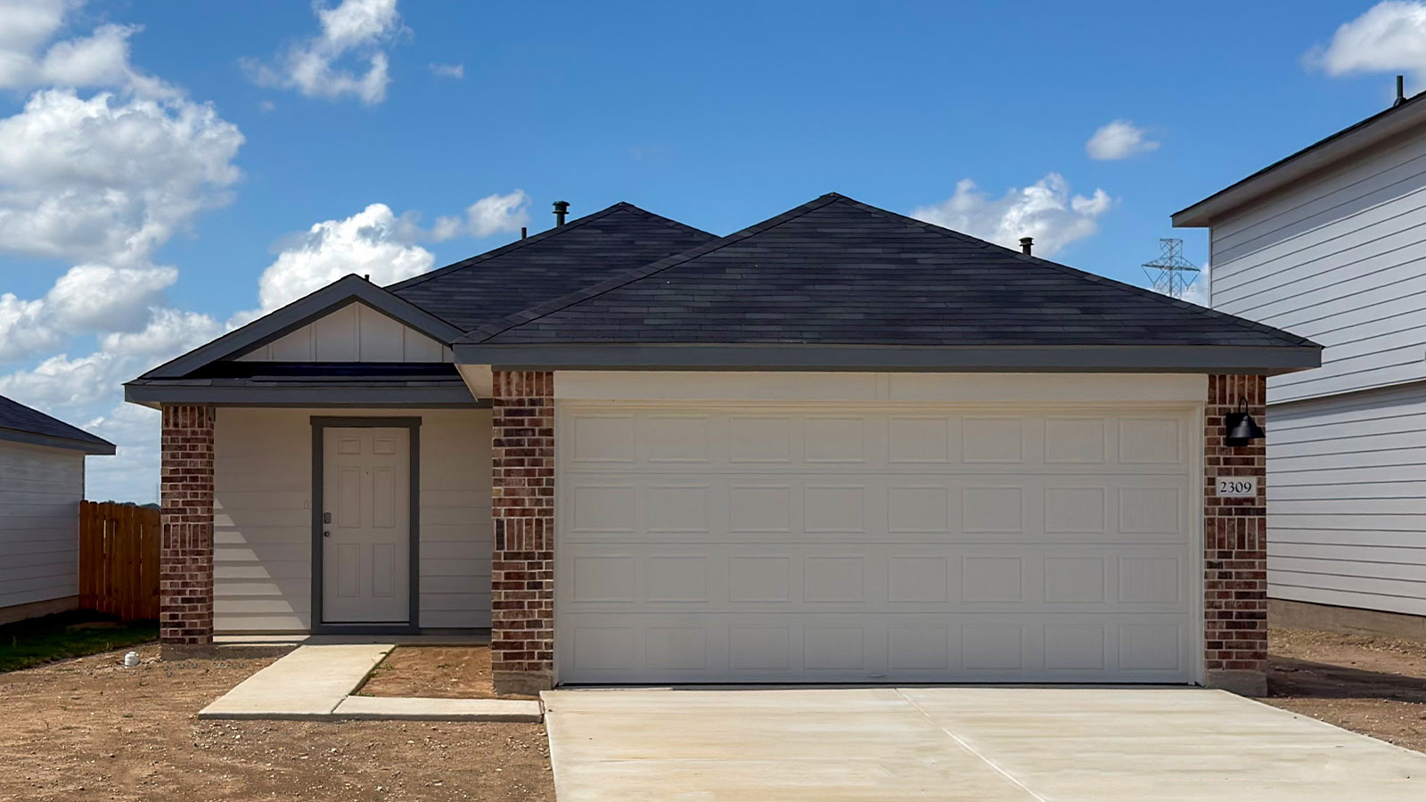 Two car garage, siding and a wrap around sidewalk to the front entry