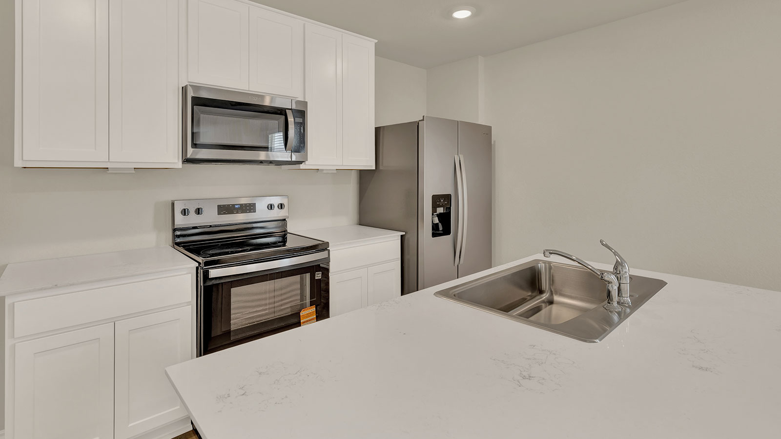 Kitchen island with quartz countertops and stainless steel appliances.