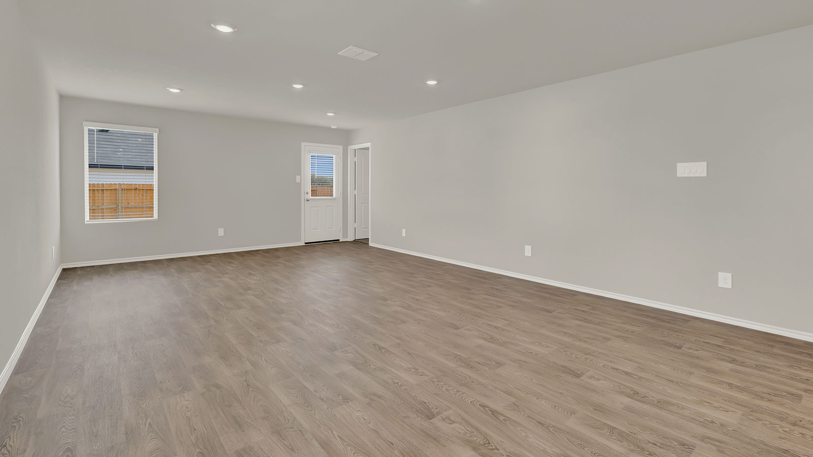Living room with vinyl flooring, windows, and a half lite exterior door.