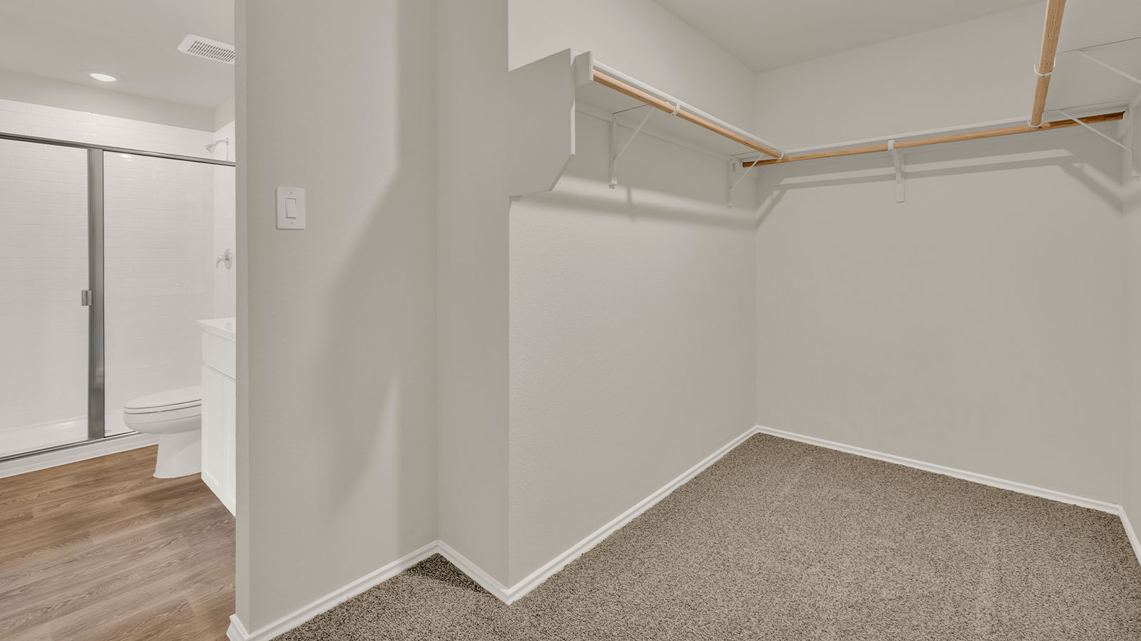 Main bedroom closet with carpeting and wooden shelving.