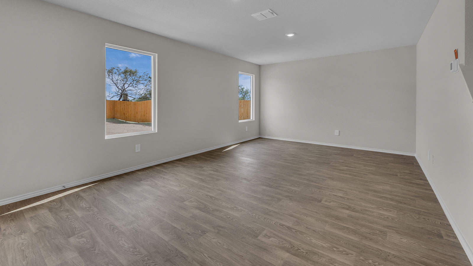 Dining room and living room with vinyl flooring and two windows.