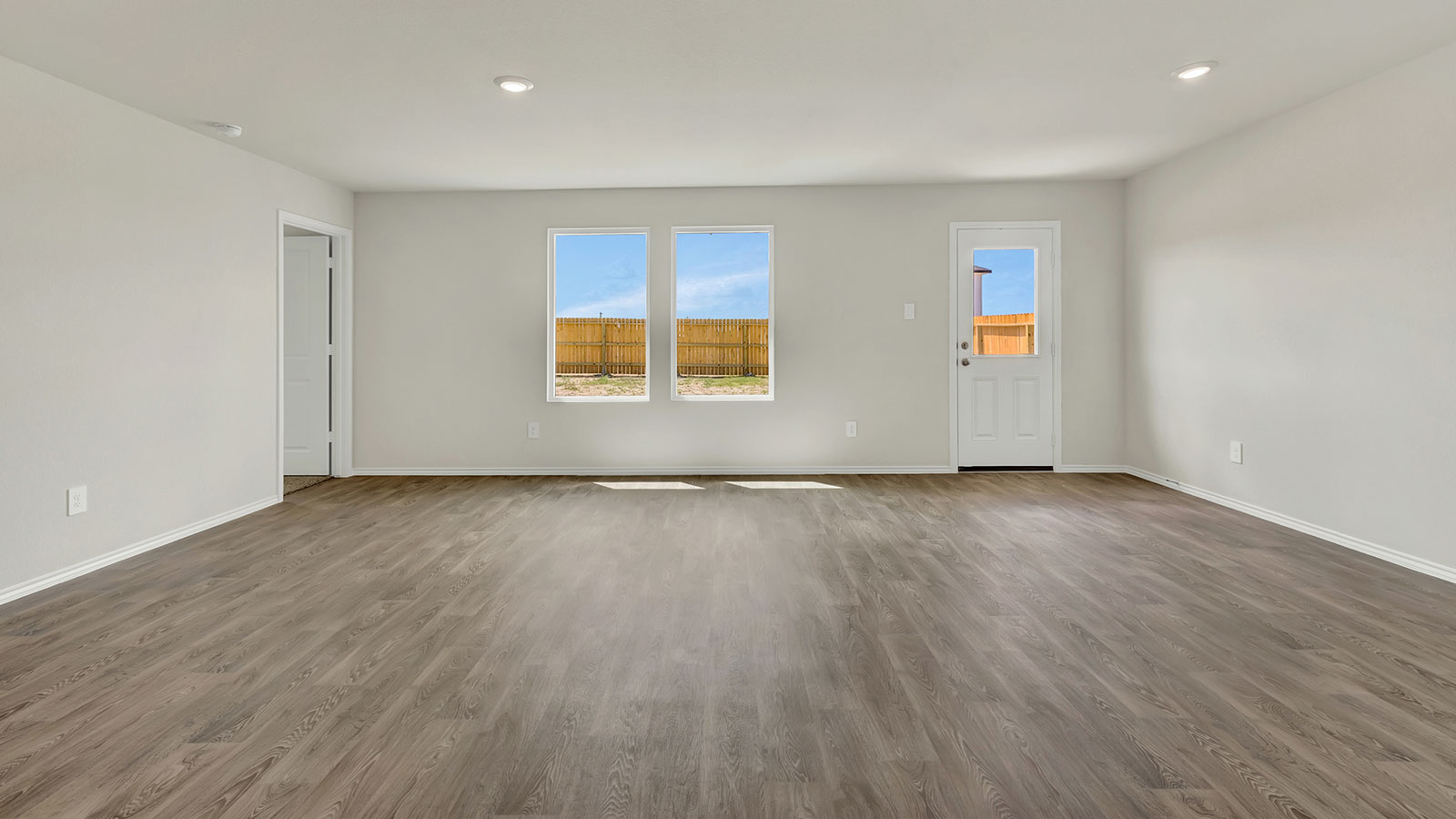 Living room and dining room with vinyl flooring, two windows, and a half lite exterior door.
