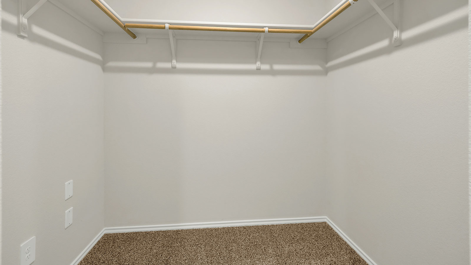 Main bedroom walk-in closet with carpeting and wooden shelving.