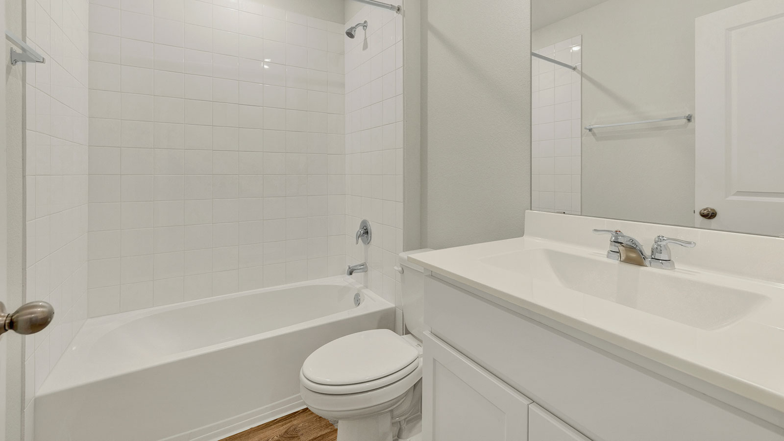 Hall bathroom with vanity, toilet, and tub with tile surround.