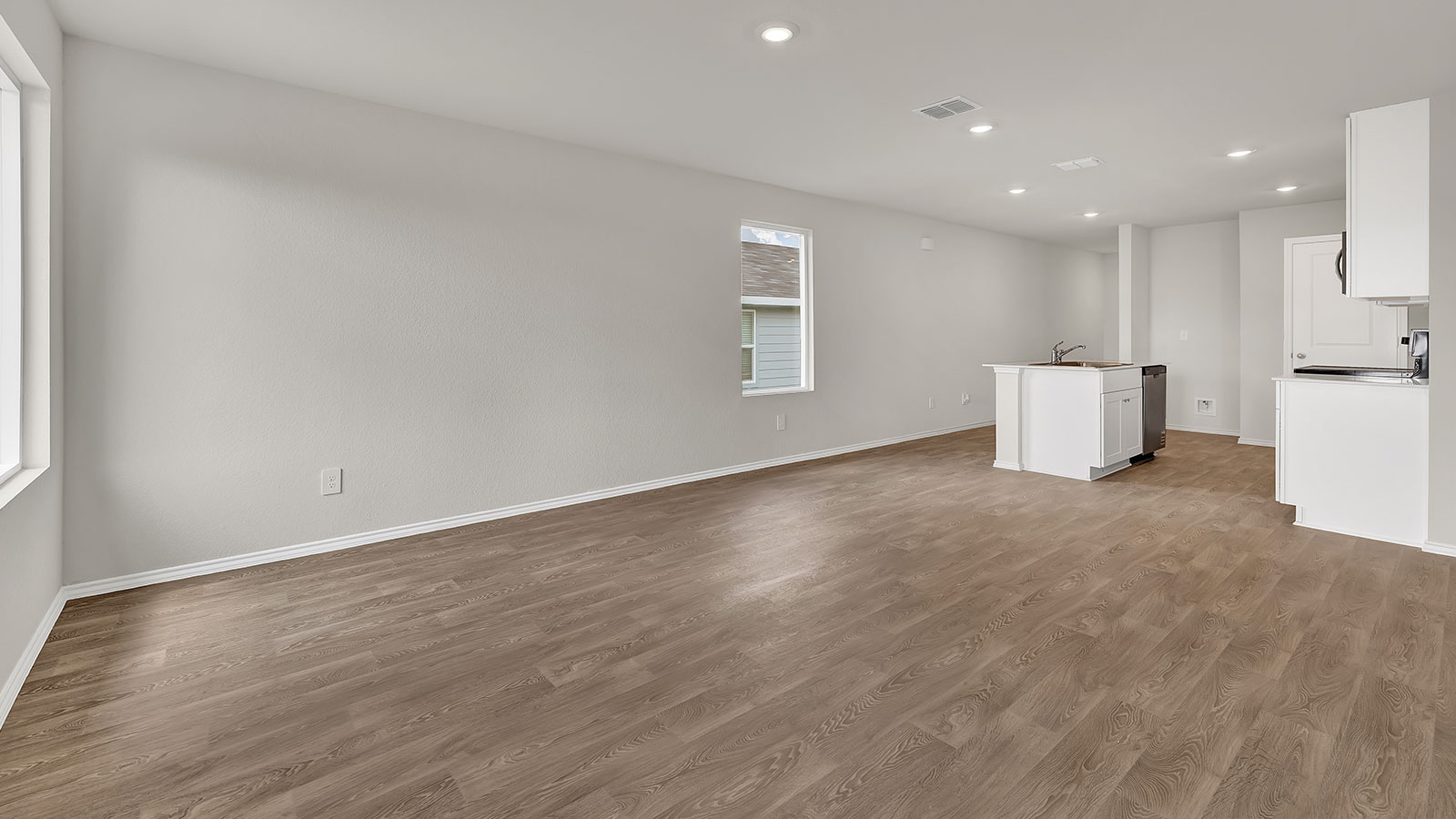 Living room with vinyl flooring opening to the kitchen.