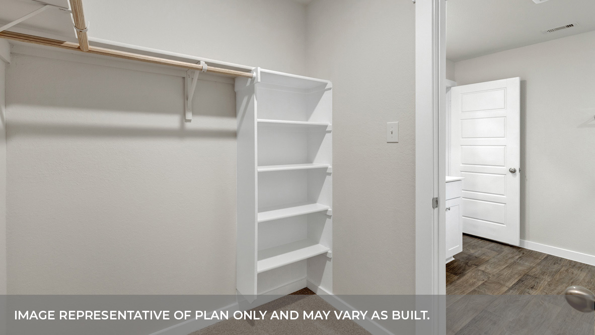 Main bedroom closet with carpeting with wooden shelving.