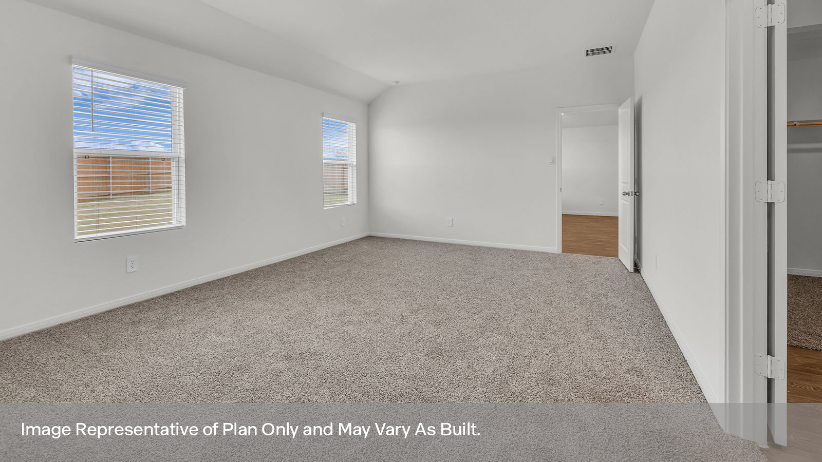 Main bedroom with carpeting and two windows.