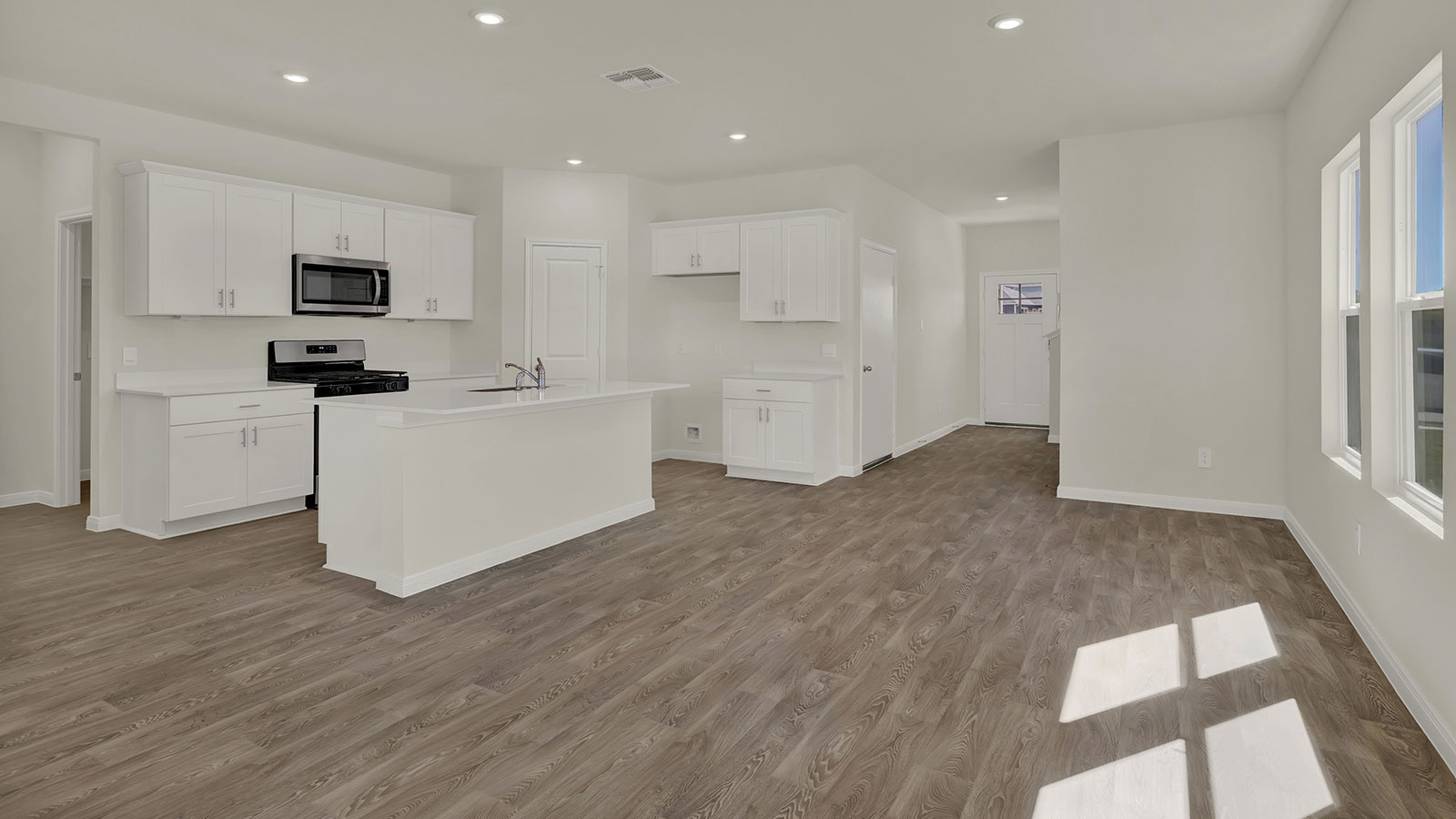 View from the living room into the kitchen and toward the front door showcasing open-concept flow.