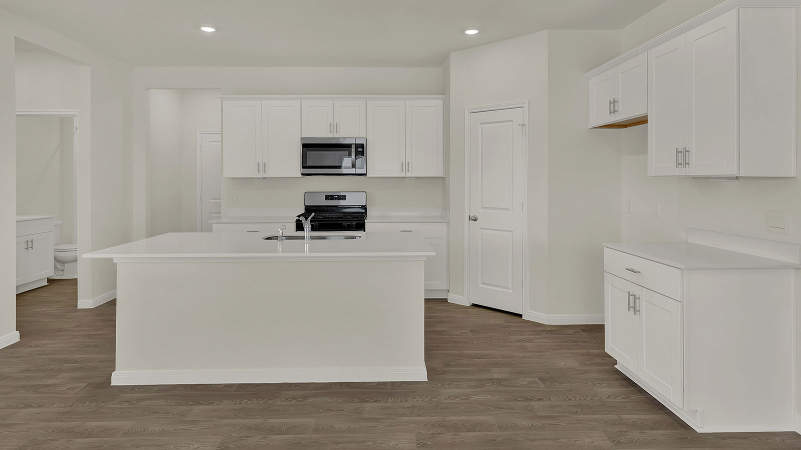 Kitchen island with sink, pantry, cabinetry, and view toward the front door supporting daily prep and organization.