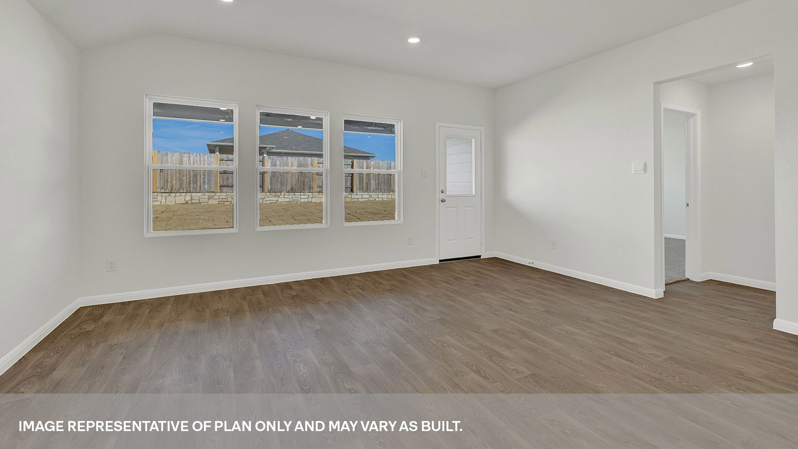 Living room with vinyl flooring, 3 windows. and a half lite exterior door.
