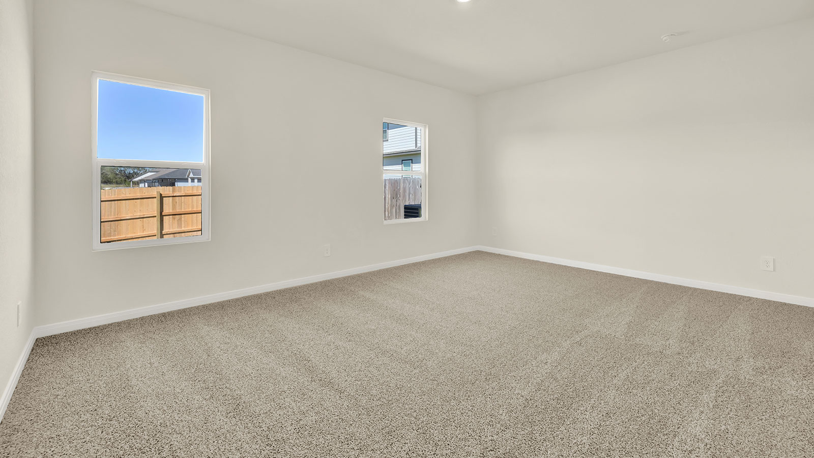 Main bedroom with carpeting and two windows.