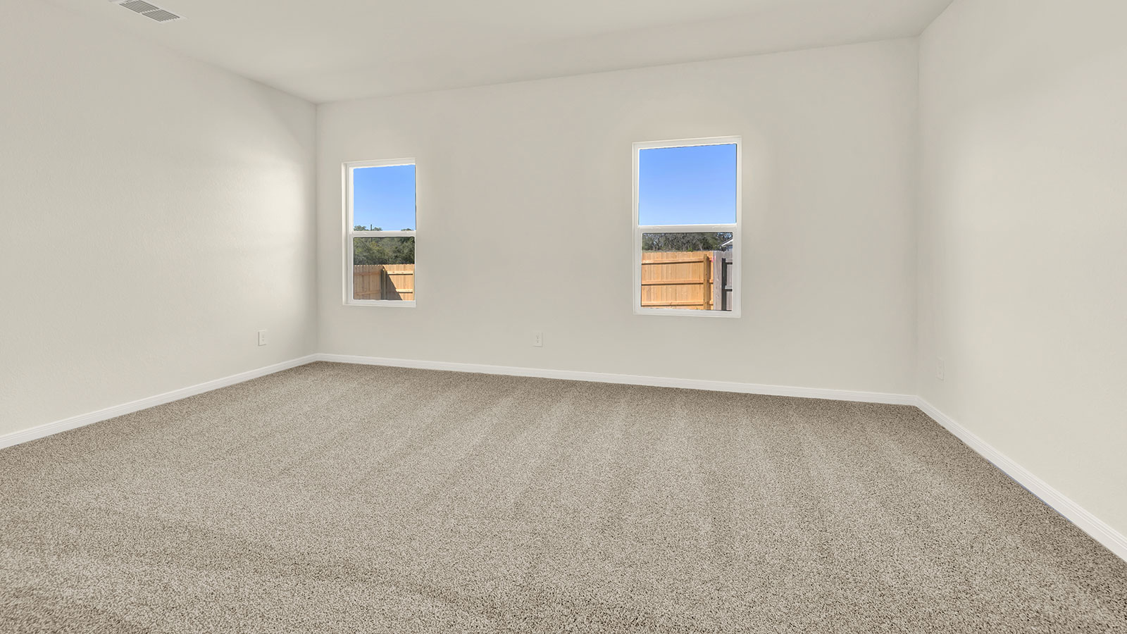 Main bedroom with carpeting and two windows.