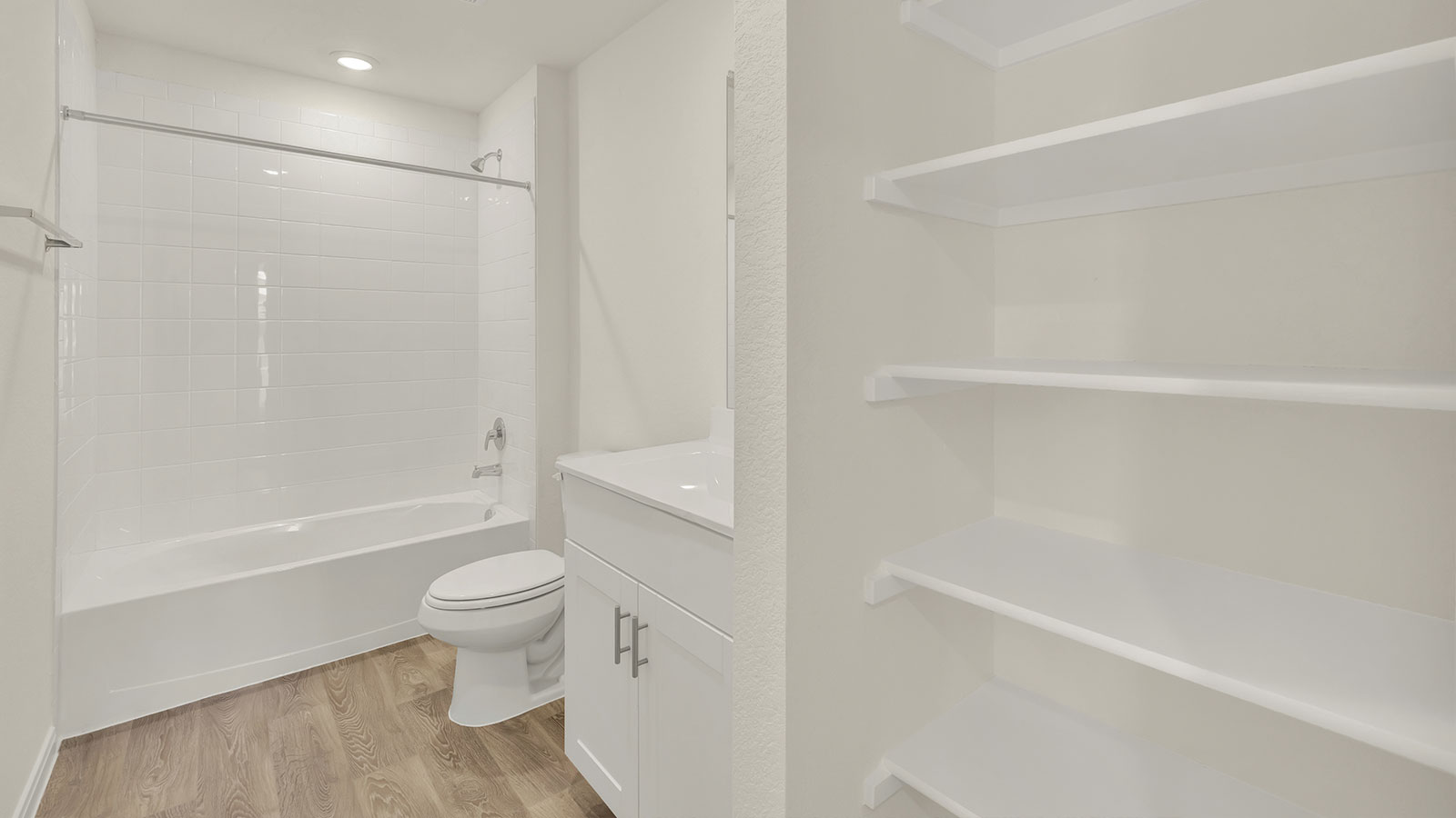 Hall bathroom with wooden shelving, toilet and tub.