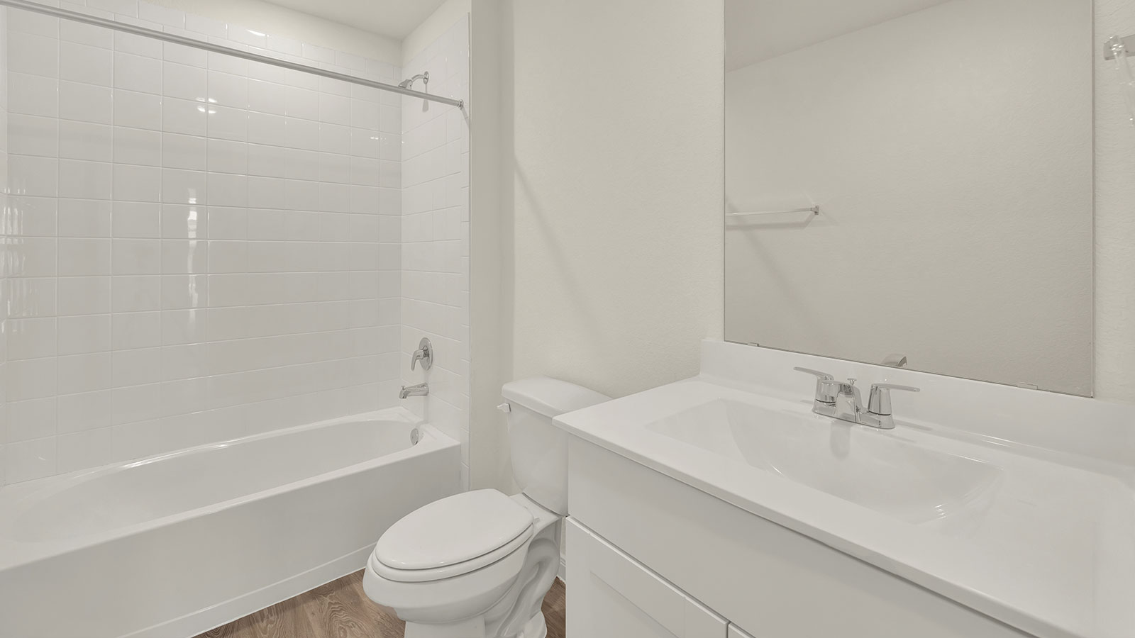 Hall bathroom with single sink vanity, toilet, and tub with tile surround.