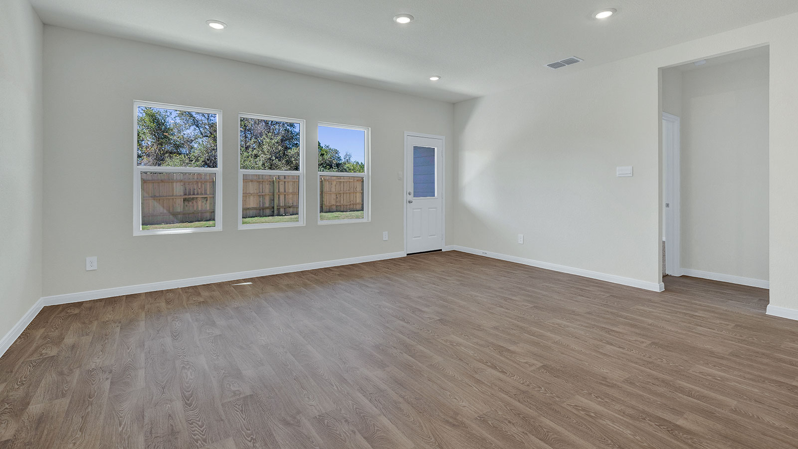 Living room with vinyl flooring and 3 windows.