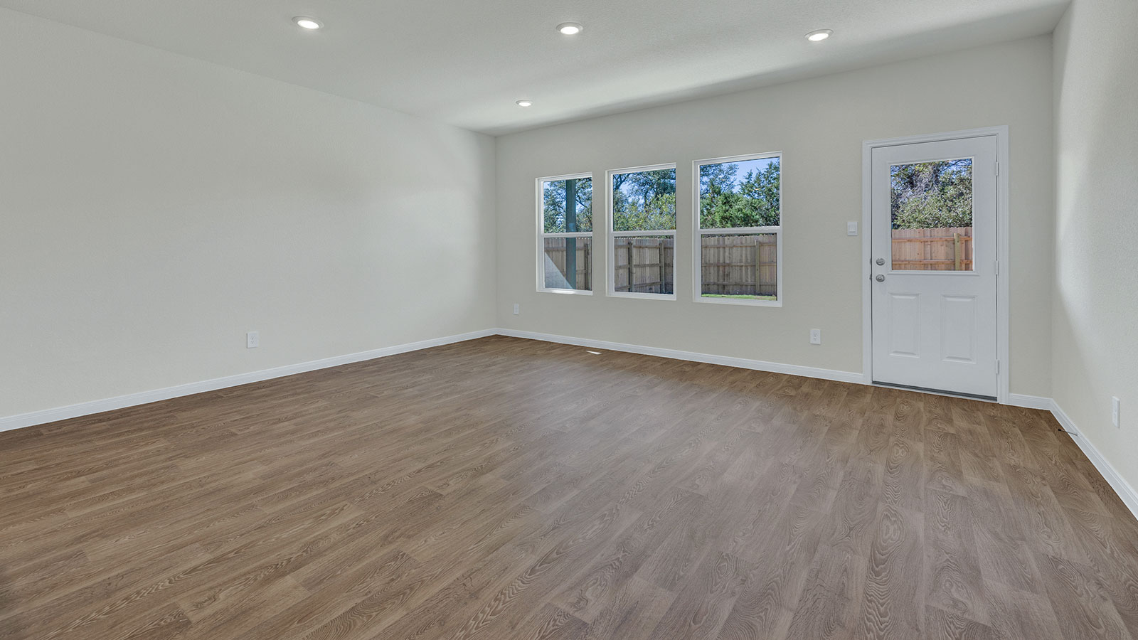 Living room with vinyl flooring and 3 windows.