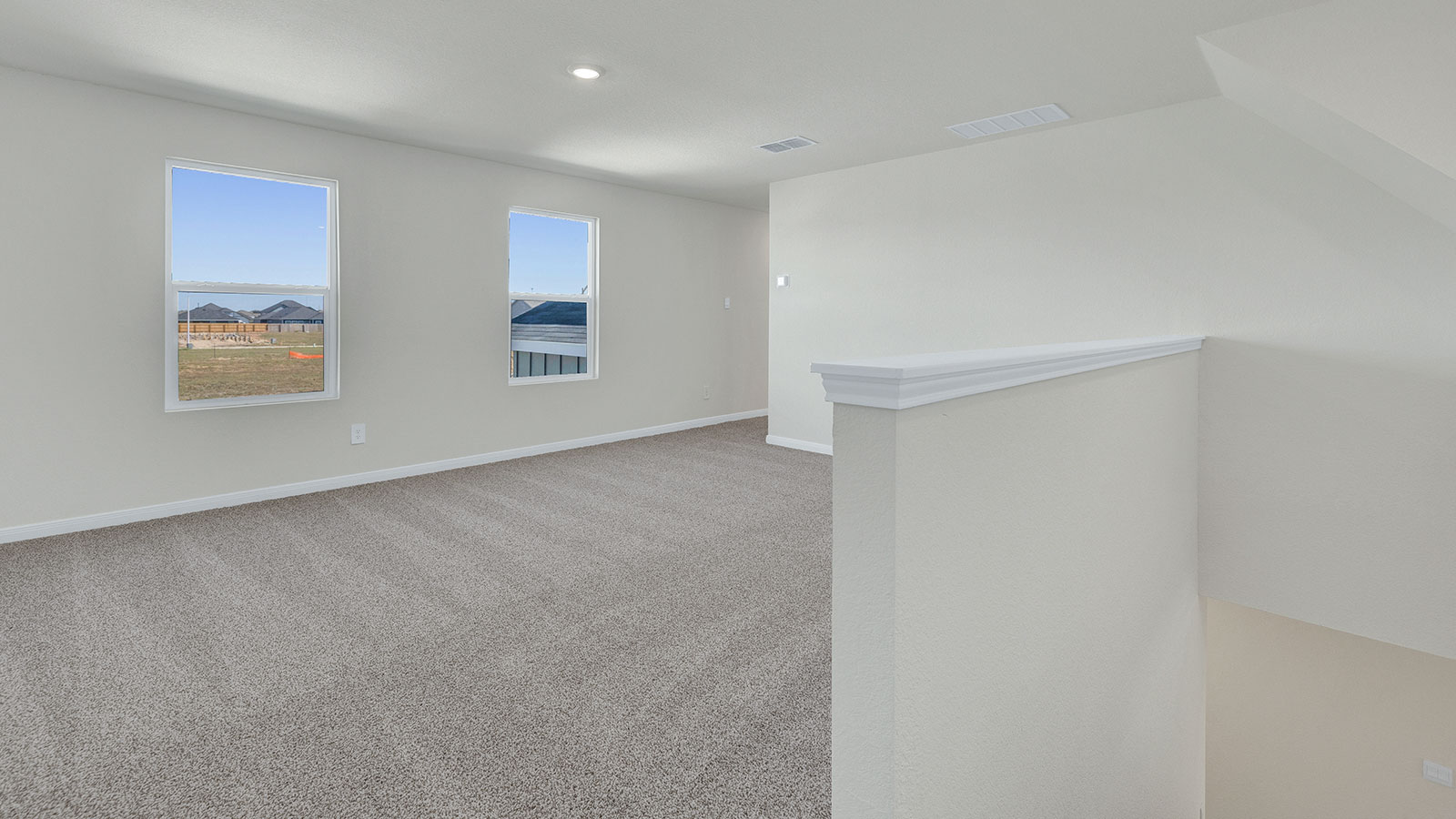 Game room off the staircase with carpeting and 2 windows.