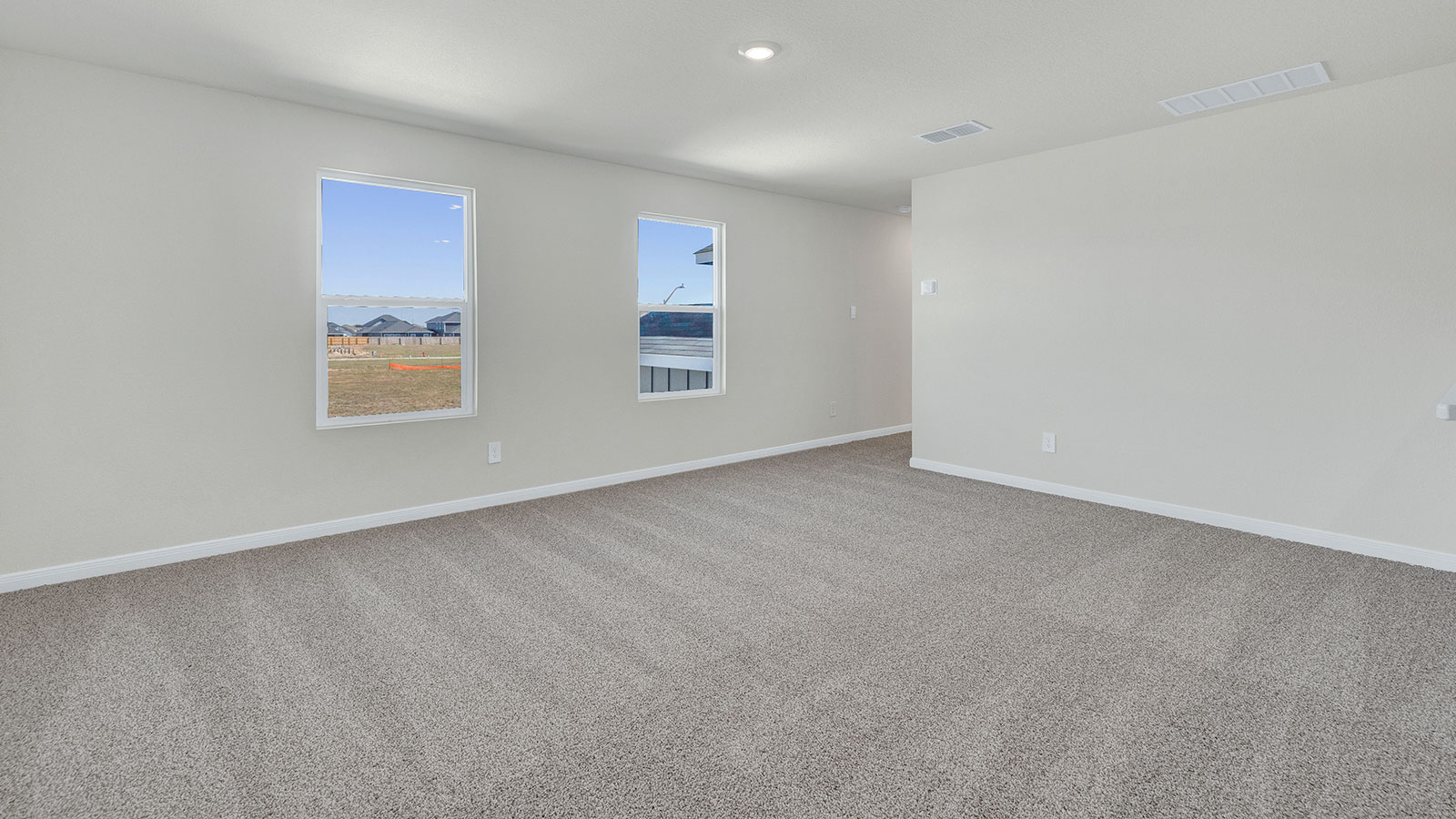 Game room off the staircase with carpeting and 2 windows.