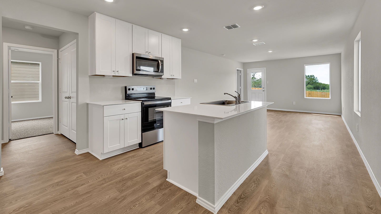 Dining room and living room with vinyl flooring, 2 windows, and a half lite exterior door.