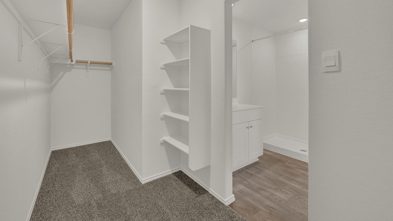 Main bedroom closet with carpeting and wooden shelving.