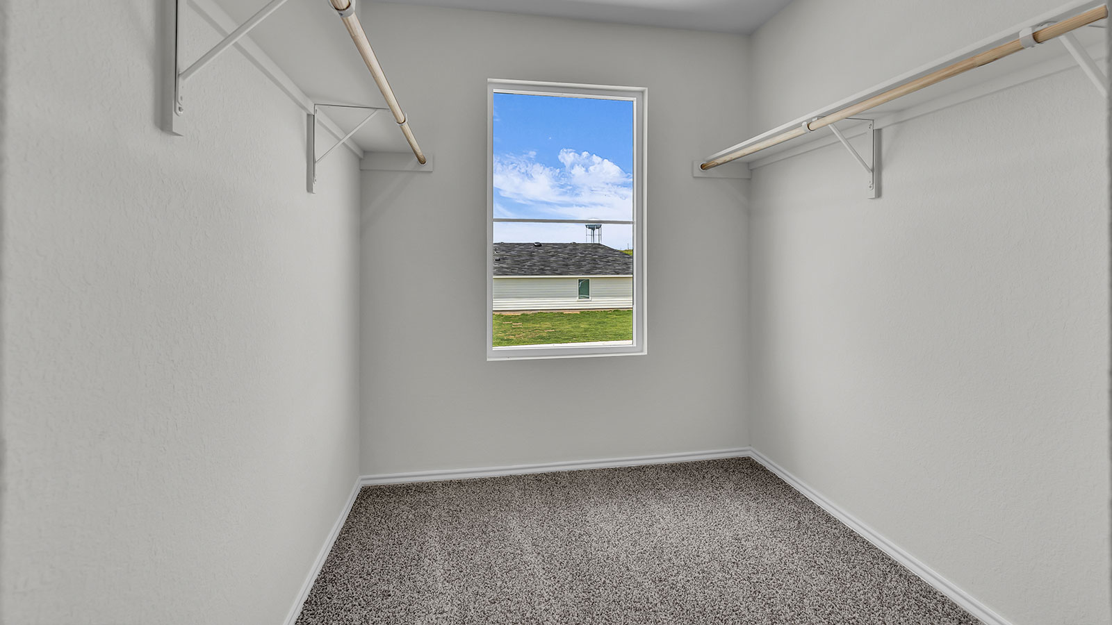 Main bedroom closet with carpeting and wooden shelving.