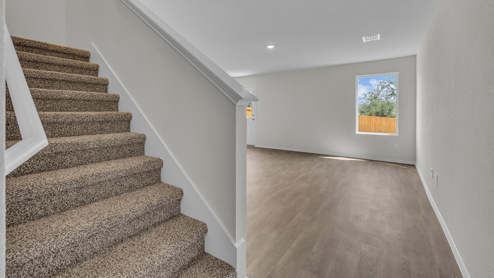 Entryway showing the front door and stairs with carpeting.