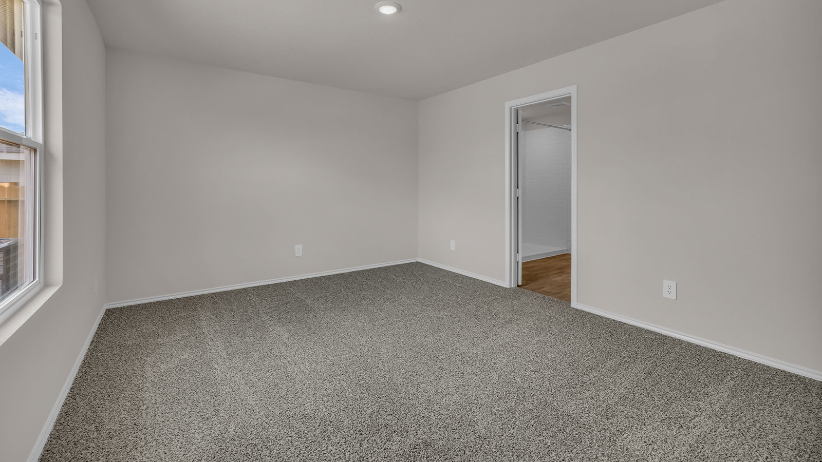 Main bedroom with carpeting and bathroom entry.