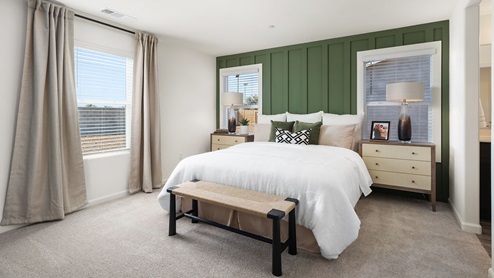 Interior photo of primary bedroom with a bed, large window, and green accent wall