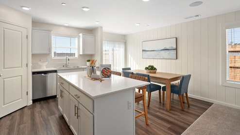 Interior photo of open concept kitchen with white counters, white cabinets, and a dining table