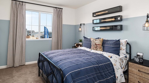 Interior photo of a kid's bedroom with a blue bed and skateboard decor on the wall