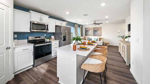 Interior photo of a kitchen with an island, barstools, and stainless steel appliacnes