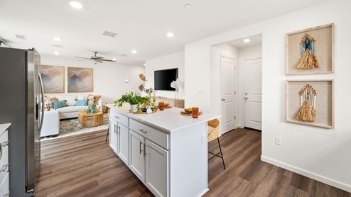 Interior photo of a kitchen island with white countertops, white cabinets, and barstools.