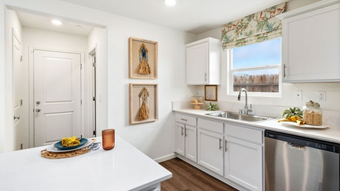 Interior photo of a kitchen with white countertops, white cabinets, and stainless steel appliances