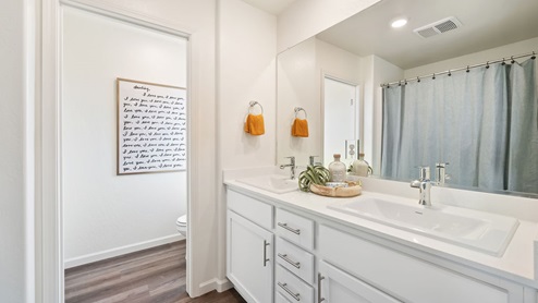 Interior photo of the primary bathroom with white counters and white cabinets