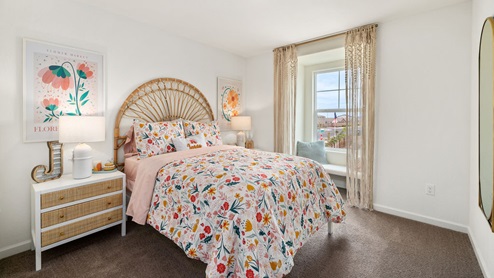 Interior photo of a kid's bedroom with a bed, endtable, and art on the walls