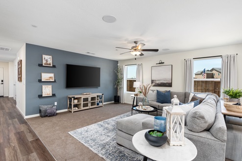 Interior photo of open concept living room with sectional couch, end tables, rug, and large windows.
