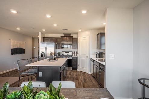 Interior photo of kitchen with dark brown cabinets, white countertops, and stainless steel appliances.