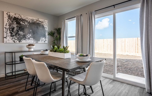 Interior photo of open concept dining room with dining table, chairs, and sliding glass door leading to backyard.