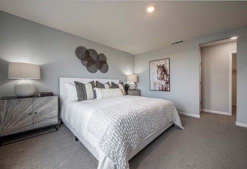 Interior photo of primary bedroom with bed and end tables.