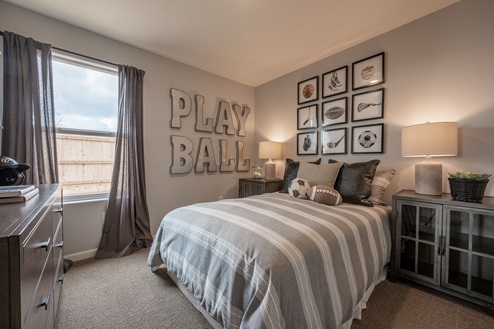 Interior photo of guest bedroom with bed, dresser, and large window.