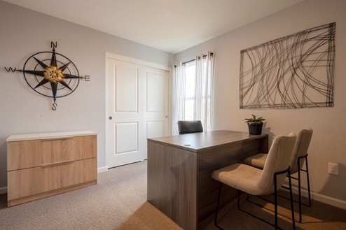 Interior photo of home office with desk, chairs, and a large window.