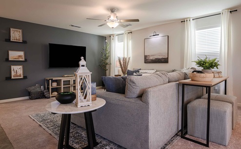 Interior photo of living room with large couch, coffee table, TV, and large windows.