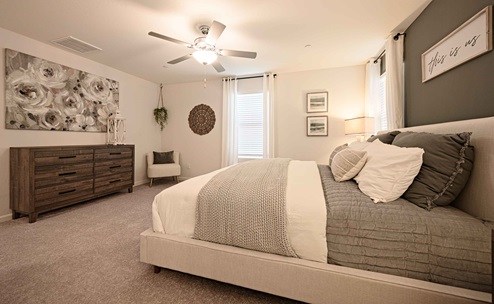Interior photo of primary suite with bed, end tables, and dresser.
