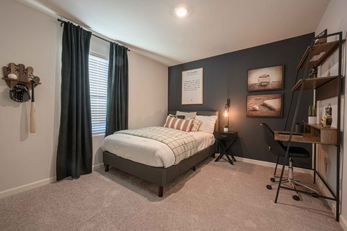 Interior photo of guest bedroom with bed, dresser, and large window.