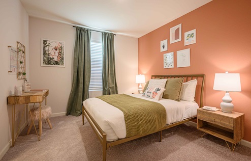 Interior photo of guest bedroom with bed, end table, and large window.