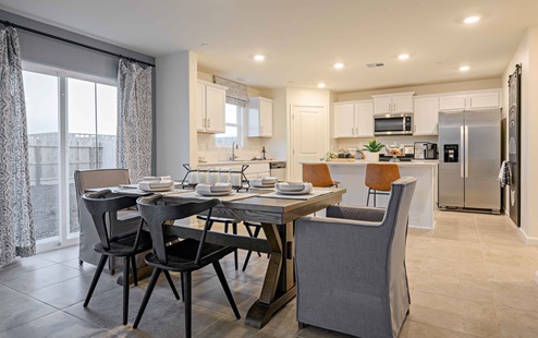 Interior photo of open concept dining room with dining table, chairs, and sliding glass door leading to backyard.