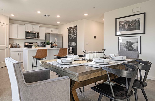 Interior photo of open concept dining room adjacent to kitchen with dining table and chairs.