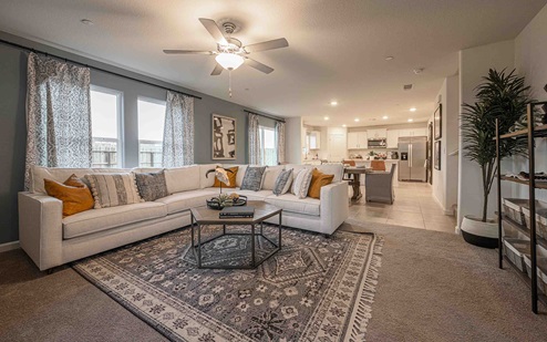 Interior photo of living room with large couch, coffee table, and large windows.